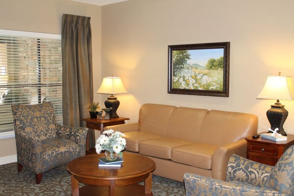 A comfortable living room with a sofa, chairs, and a painting.