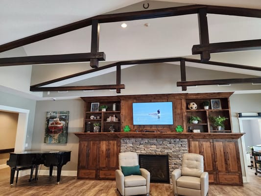 Cozy living room featuring a piano, two chairs, and a mounted TV.