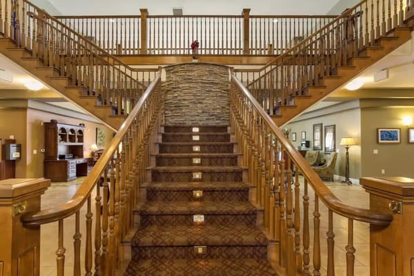 Wooden staircase leading to the upper floor in a senior living lobby