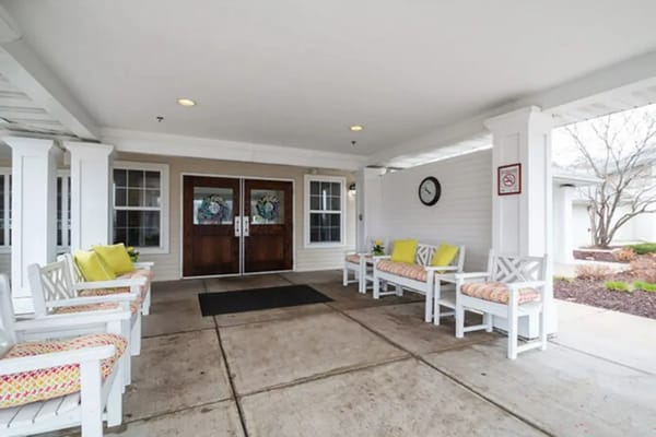 Entrance with white benches and colorful cushions at Trustwell Living Cherryvale Place.