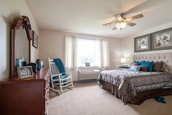 A cozy bedroom with a bed, dresser, and a rocking chair