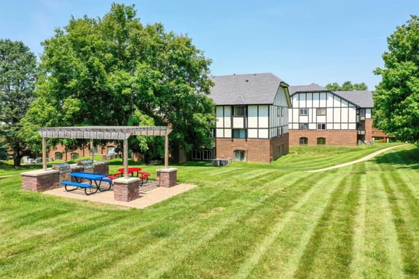 Picnic area with tables and grills surrounded by green lawn at Tudor Heights