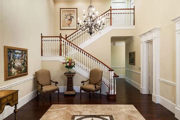 Entryway featuring a staircase, armchairs, and decorative artwork.