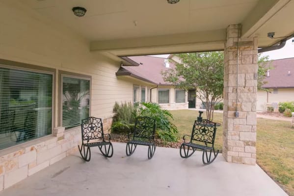 Three decorative chairs on a patio outside a senior living facility.