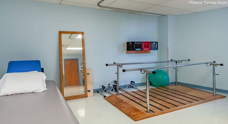 A physical therapy room featuring a therapy bar, exercise equipment, and a mirror.