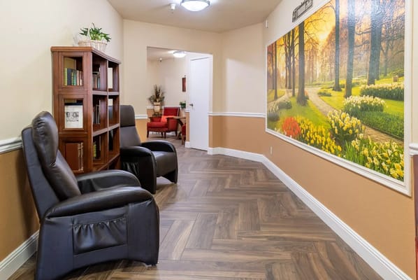 Cozy living area with black recliners and a scenic mural