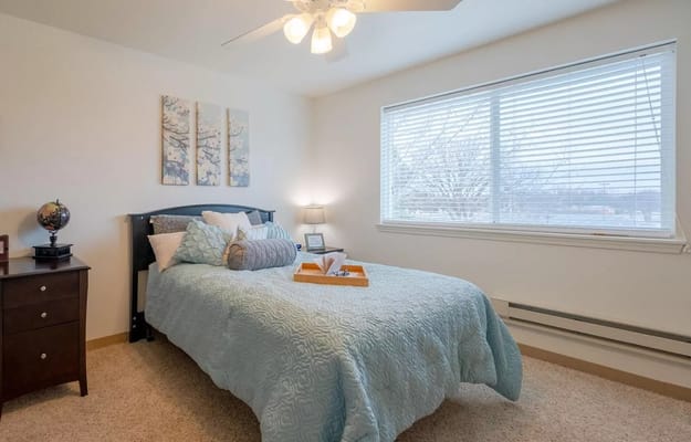 A well-decorated bedroom with a bed, bedside table, and window.
