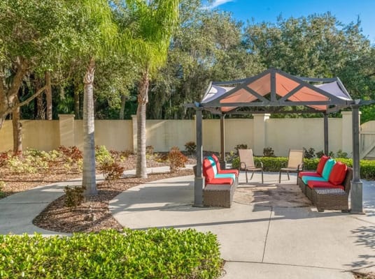 A cozy outdoor lounge area with colorful seating and a shaded pergola.