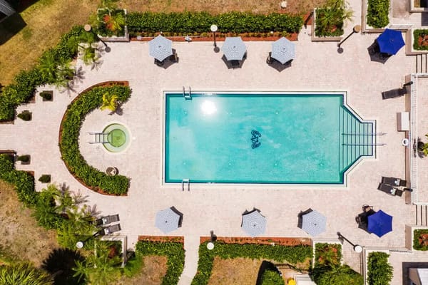 Aerial view of a swimming pool surrounded by greenery and umbrellas at Veranda Club.