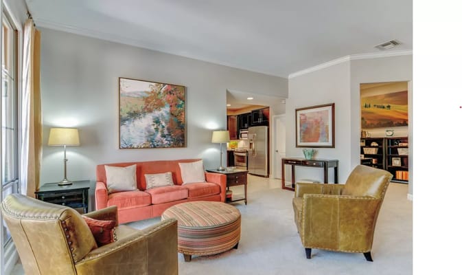 Cozy living room with a sofa, two chairs, and artwork on the walls.