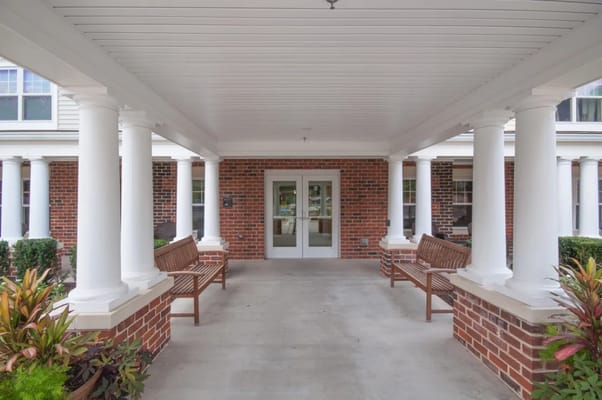Entrance area with benches and columns at Victory Court Senior Apartments