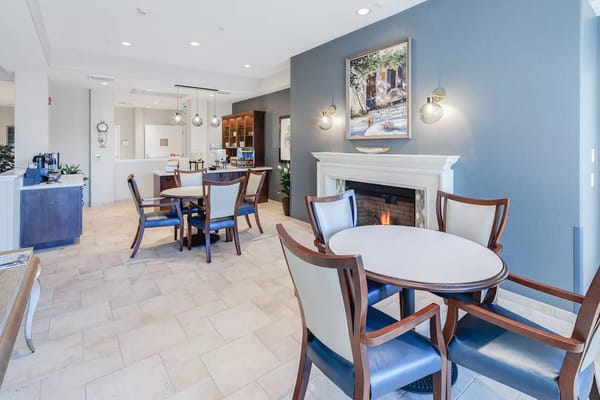 Cozy common area with tables and chairs, fireplace, and artwork