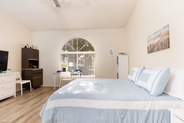 Brightly lit resident room with a bed and desk