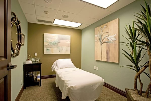 A quiet treatment room with a massage bed and artwork.