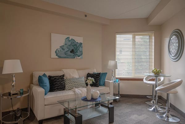Cozy living room featuring a white sofa, decorative pillows, and a glass coffee table.