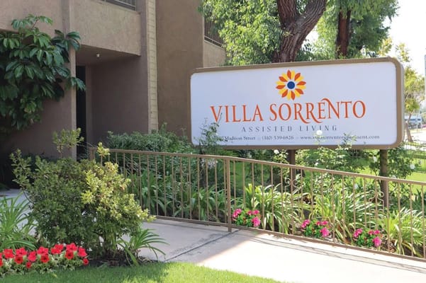 Sign for Villa Sorrento Assisted Living surrounded by greenery.