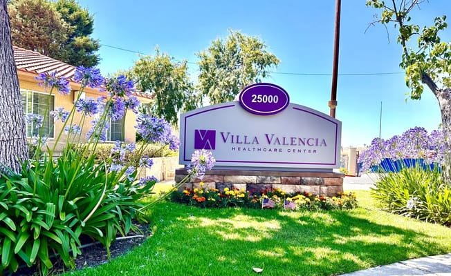 Sign for Villa Valencia Healthcare Center surrounded by flowers
