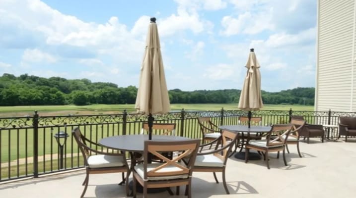 Outdoor patio seating with umbrellas overlooking green fields