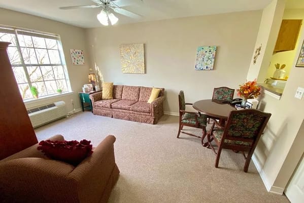 Cozy living space with a couch and dining table in Ville Ste Marie Senior Living.