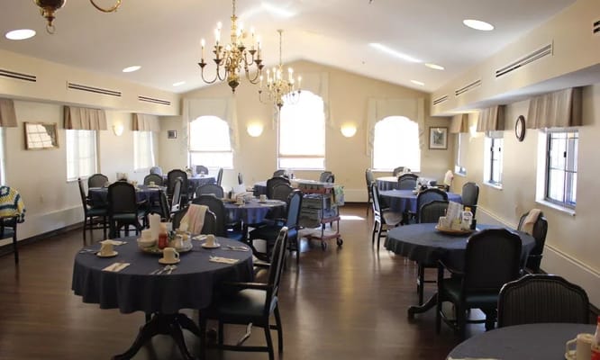 Interior view of the dining room with round tables and a chandelier.