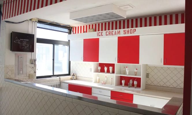 Brightly colored ice cream shop with red and white cabinets.