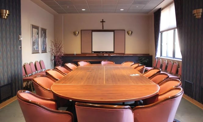 Meeting room with a large wooden table and red chairs