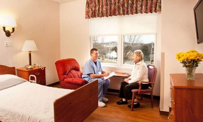A caregiver and resident engaging in conversation in a cozy room at Vincentian Home.