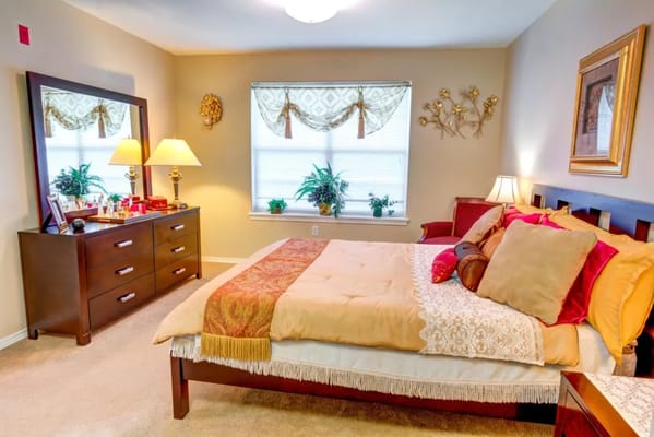A cozy bedroom featuring a bed, dresser, and decorative elements.