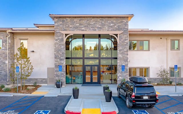 Front entrance of Vista at Simi Valley with large glass doors and stone facade