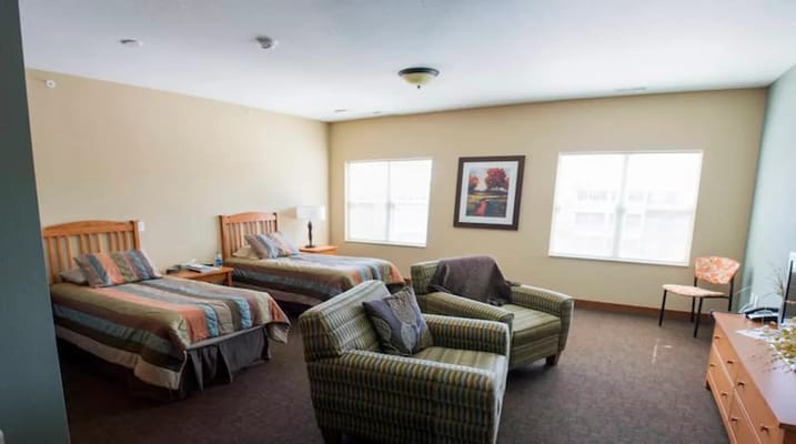 A cozy room with two beds and comfortable seating at Walker Methodist - Westwood Ridge.