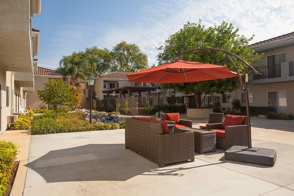 Cozy outdoor seating area with red umbrella and lush landscaping