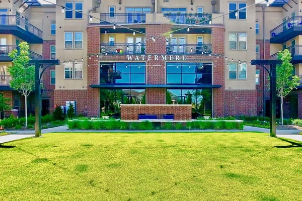 View of the courtyard at Watermere at Frisco featuring landscaped grass and the facility's entrance