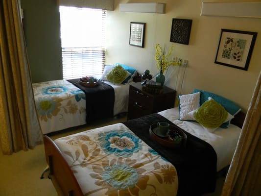 A double bedroom with two beds, decorative pillows, and a window with blinds.