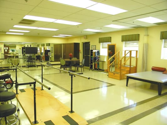 Therapy room with exercise equipment and rehabilitation tools.