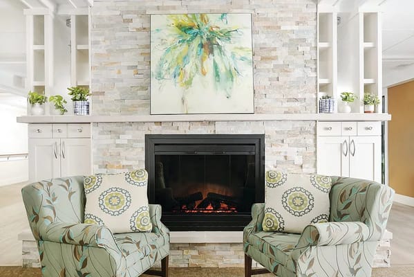 Cozy seating area featuring two chairs and a fireplace.