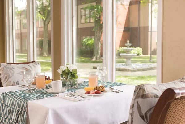 Table set for breakfast with juice, coffee, and fruit in a dining area