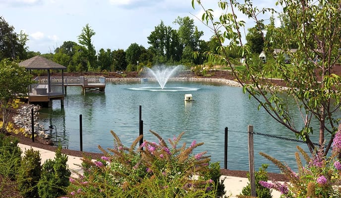 Beautiful outdoor pond with fountain and surrounding flowers