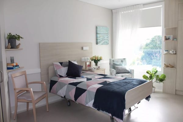 A well-decorated resident room with a bed and seating area