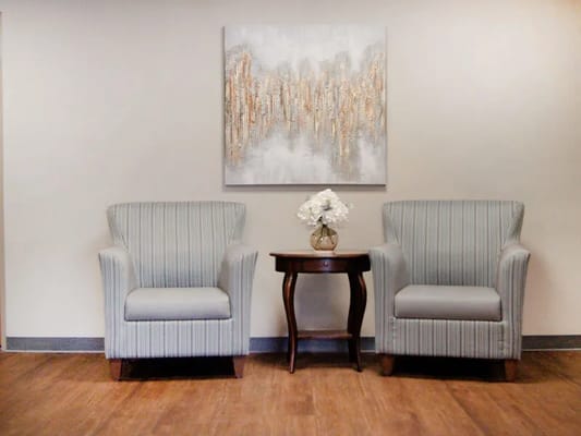 Two striped armchairs with a side table and decorative flowers