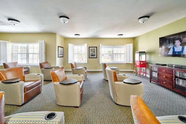 Cozy lounge with chairs and a popcorn machine, featuring a TV screen.