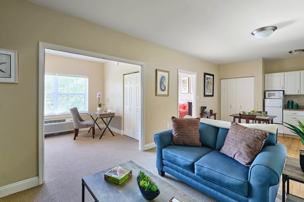 Cozy living room with a blue sofa and adjacent dining area.