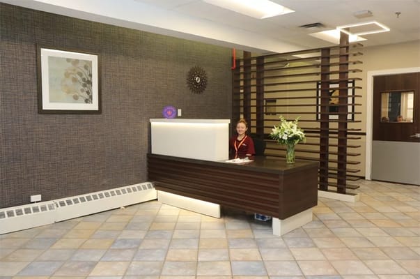 Reception area with a staff member and floral arrangement