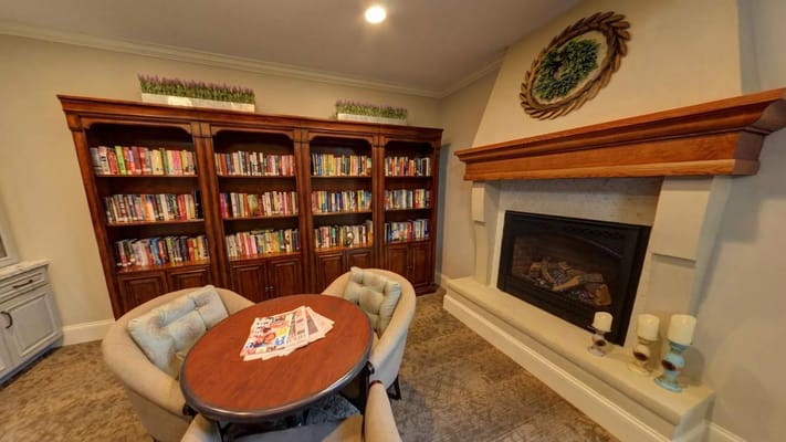 Library corner with bookshelves and seating at Willow Falls Senior Living