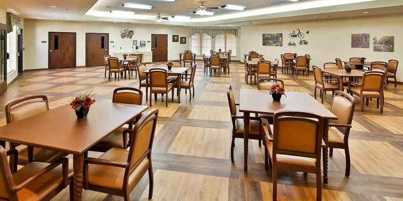 Spacious dining room with wooden tables and chairs, adorned with flower centerpieces.