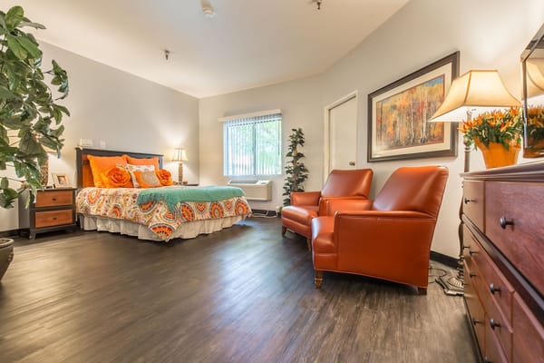 Brightly decorated resident room with a bed and seating area