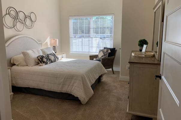 A well-decorated bedroom with a bed, lamp, and seating area.