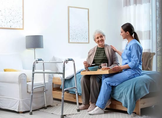 Staff member serving a meal to a resident in a bright room