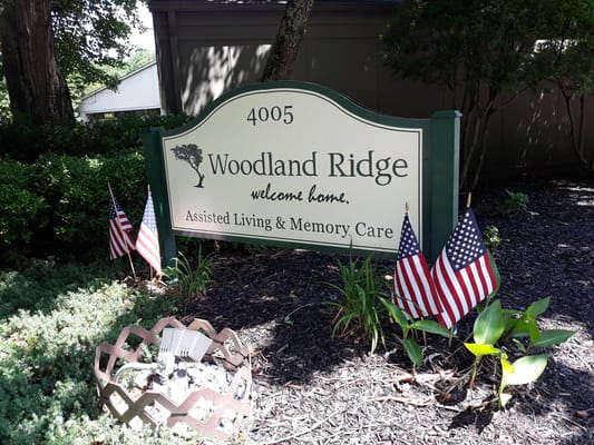 Sign for Woodland Ridge Assisted Living with American flags