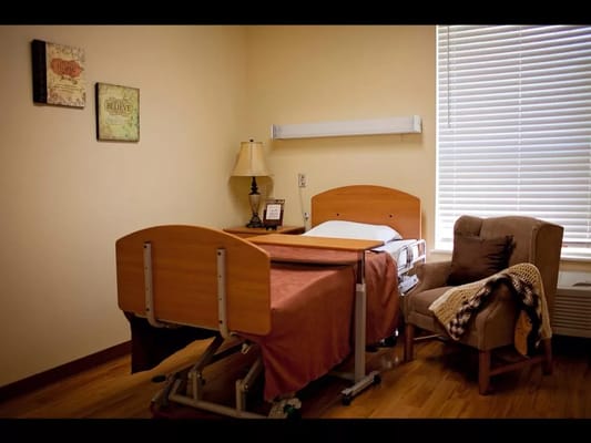 A hospital bed with a side chair and lamp in a private room.