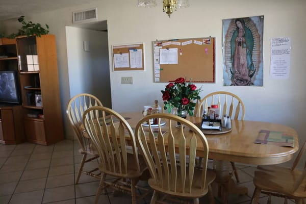 A dining room with wooden chairs, a table set for meals, and decorative elements.